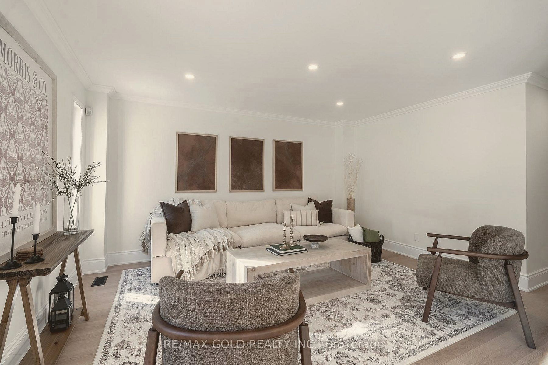 Family room staged with a cream sofa, tonal triptych art and textured accent chairs